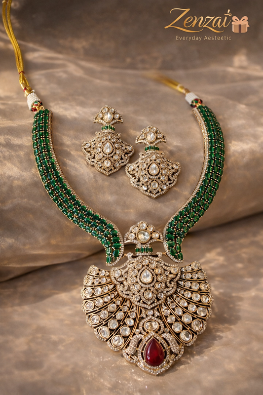 Zenzai green polki necklace set with fan-shaped pendant, ruby accent, green beaded chain and pearl drop earrings styled on a soft fabric background